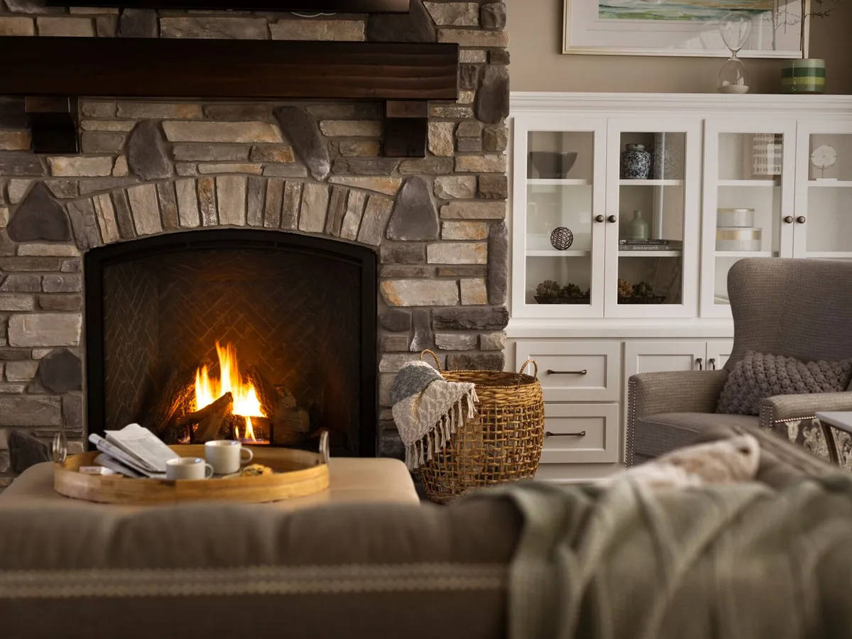 Heat & Glo gas fireplace in a stone surround with a wood mantel and white built-in cabinets